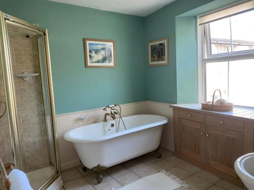 a bathroom with a tub and a shower and a sink at Harbour Cottage in Watchet