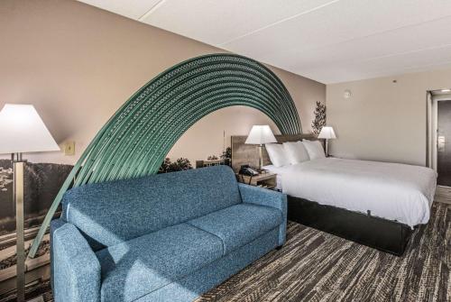 a hotel room with a bed and a blue couch at Clarion Pointe Near University in Rock Hill