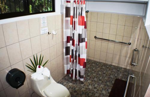 a bathroom with a shower curtain and a toilet at Hotel Arenal Country Inn in Fortuna