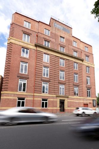 a red brick building with cars speeding past it at Mantra One Sandy Bay Road in Hobart
