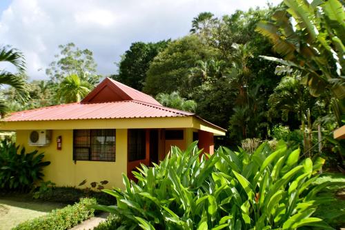 a small yellow house with a red roof at Hotel Arenal Country Inn in Fortuna