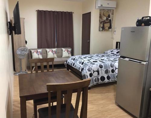 a bedroom with a bed and a table and a refrigerator at Bria Flats/Codo in Cagayan de Oro