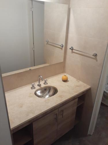 a bathroom sink with a mirror and an orange on it at Casa Elisa in Ciudad Lujan de Cuyo