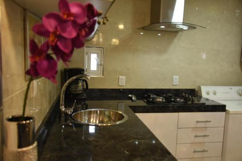 a kitchen with a sink and a vase with purple flowers at Departamento Alejandro - Completo y Amplio Departamento en una zona muy tranquila de la CDMX in Mexico City