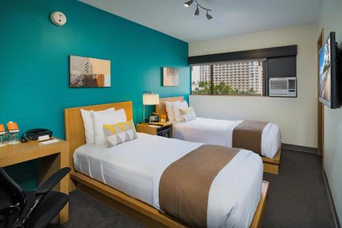 a hotel room with two beds and a blue wall at VIVE Hotel Waikiki in Honolulu
