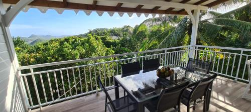 a table and chairs on a balcony with a view at Residence Can' Hibiscus in Le Marin