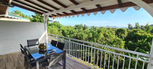 a balcony with a table and a view of trees at Residence Can' Hibiscus in Le Marin