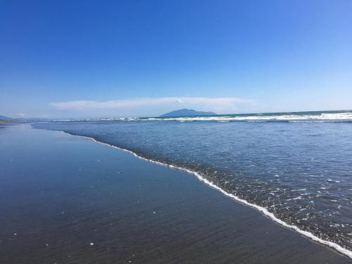 an empty beach with waves in the ocean at Sand Dunes Retreat in Otaki Beach