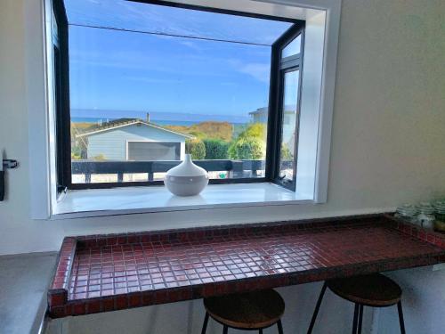 a window with a vase sitting on top of a counter at Sand Dunes Retreat in Otaki Beach