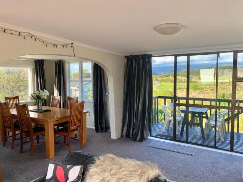 a living room with a table and chairs and a balcony at Sand Dunes Retreat in Otaki Beach