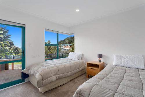 a bedroom with two beds and a balcony at The Lights House - Beachfront Ohope Holiday Home in Ohope Beach