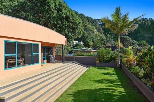 a house with a wooden deck next to a yard at The Lights House - Beachfront Ohope Holiday Home in Ohope Beach