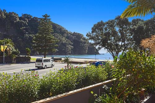 a white van driving down a road next to a beach at The Lights House - Beachfront Ohope Holiday Home in Ohope Beach