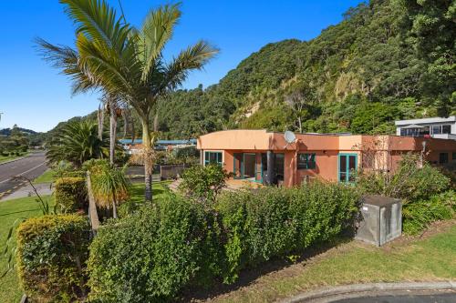 a house on the side of a road with palm trees at The Lights House - Beachfront Ohope Holiday Home in Ohope Beach