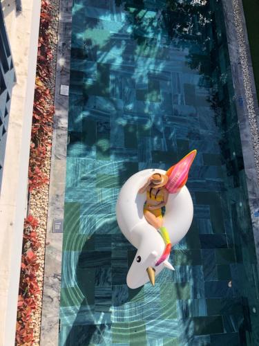 a woman riding on a surfboard in a swimming pool at Lavini Hoian Boutique Villa in Hoi An