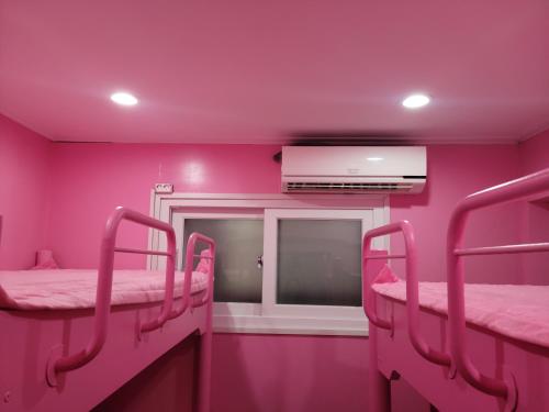 a pink room with two bunk beds and a window at Jeju Vision House in Jeju