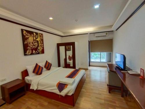 Schlafzimmer mit einem Bett, einem Schreibtisch und einem TV in der Unterkunft WeRest Hotel in Khon Kaen