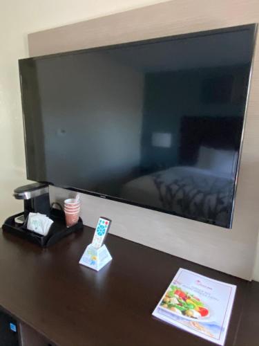 a large flat screen tv hanging on a wall at Ocean Sands Beach Boutique Inn-1 Acre Private Beach-St Augustine Historic-2 Miles-Shuttle with Downtown Tour-HEATED Salt Water Pool until 420AM-Popcorn-Cookies-New 4k USD Black Beds- 69 Item Breakfast-Eggs-Bacon-Starbucks- Free Laundry- #904-799-SAND in Saint Augustine