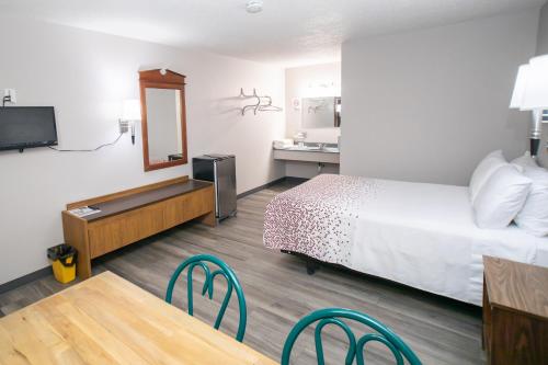 a hotel room with a bed and a table and a sink at Shady Rest Motel in Arapahoe