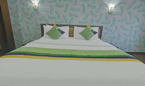 a bedroom with a white bed with green pillows at Treebo Savoury Sea Shell Residency in Bengaluru