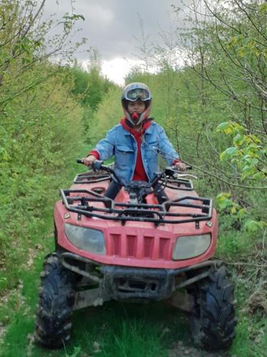 a person sitting on a atv in the woods at Pensiunea Natura Sadu in Sibiu