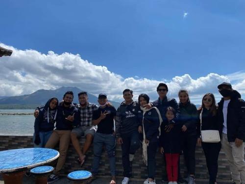 a group of people posing for a picture in front of the water at Batur Green Lakeview in Kintamani Bali in Kintamani