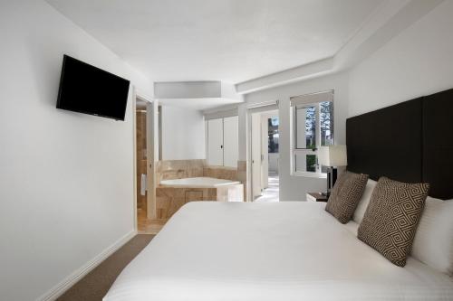 a bedroom with a large white bed and a television at Mantra Zanzibar in Mooloolaba