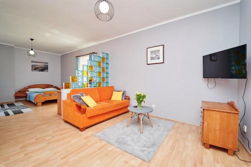 a living room with an orange couch and a table at Hotelik Gołdap in Gołdap