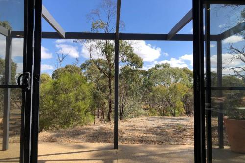an open glass door with a view of a field at Benny's Retreat Luxury Bushland Escape in Clare