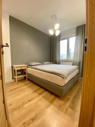 1 dormitorio con cama, mesa y ventana en Comfortable apartments Warsaw West III, en Varsovia