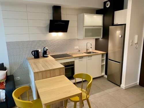 cocina con mesa de madera y sillas amarillas en Comfortable apartments Warsaw West III, en Varsovia