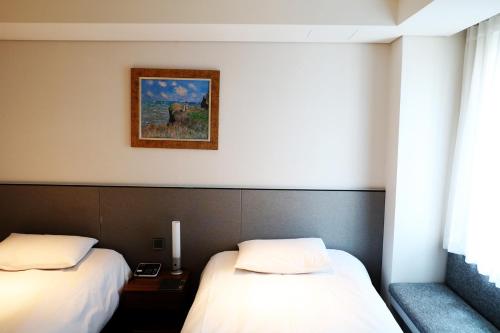 a room with two beds and a picture on the wall at Hotel Thomas Myeongdong in Seoul