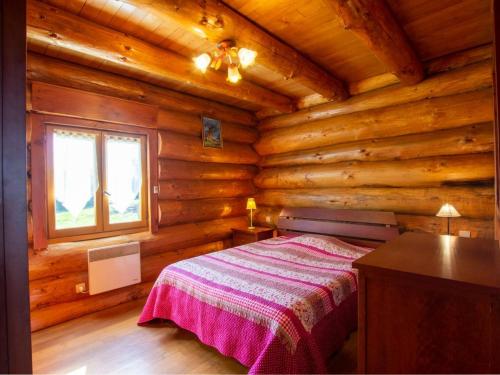 Un dormitorio con una cama en una cabaña de troncos en Chalet de charme avec étang privé : pêche, nature et détente au cœur du Périgord - FR-1-616-72, en Dussac