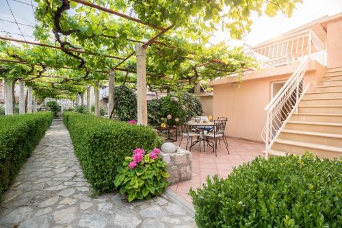 un patio con mesa, sillas y arbustos en Apartments Lotea, en Cavtat