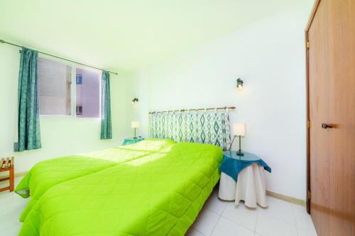 a bedroom with a green bed and a window at Apartamento Grillo in Cala Ratjada