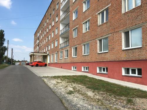 a red car parked next to a brick building at Hotel Elegia in Trostyanets