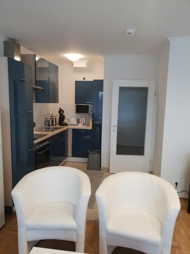 two white chairs in a kitchen with blue cabinets at Ferienwohnung Finkenweg in Bad Neuenahr-Ahrweiler