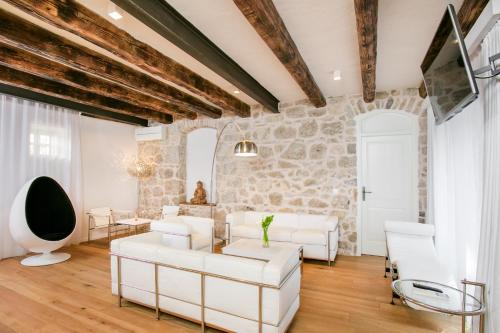 a living room with white furniture and a stone wall at Divota Apartment Hotel in Split