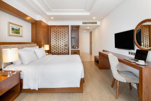 a bedroom with a bed and a desk with a computer at Paris Deli Danang Beach Hotel in Da Nang