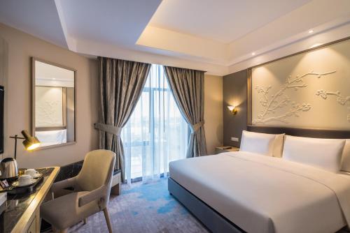 a hotel room with a bed and a desk and a window at Aber Khamis Mushait in Khamis Mushayt