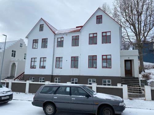 a car parked in front of a white house at Day Dream Central Akureyri Two Bedroom Apartment in Akureyri