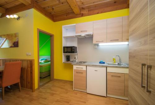 a kitchen with yellow walls and wooden cabinets at Penzion Sidorovo in Ružomberok