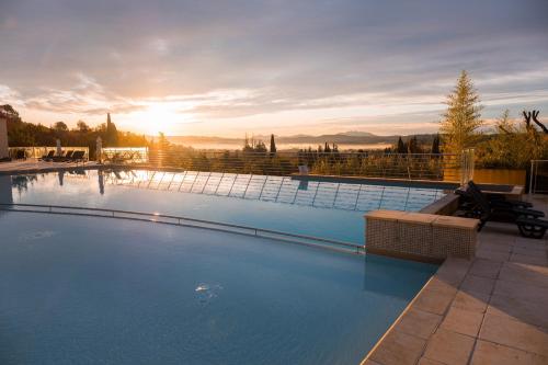 ein großer Pool mit Sonnenuntergang im Hintergrund in der Unterkunft Vacancéole – Le Domaine de Camiole in Callian
