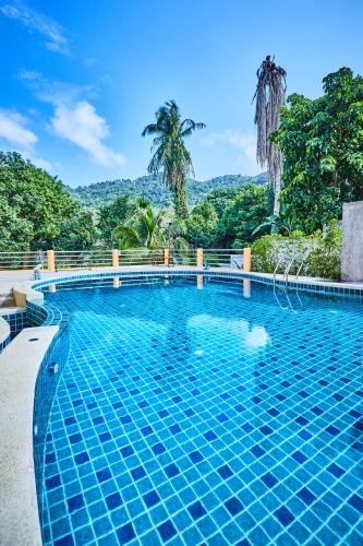 a swimming pool in a resort with mountains in the background at Coco Palm Hotel Koh tao in Koh Tao