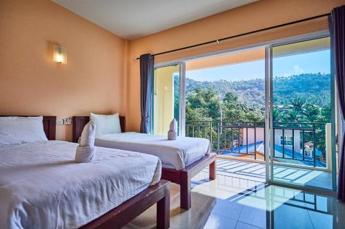 a bedroom with two beds and a large window at Budchui Village2 in Ko Tao