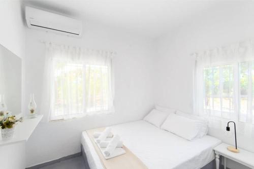 a white living room with a white couch and windows at Family Maisonette with pool #3 in Nea Fokea