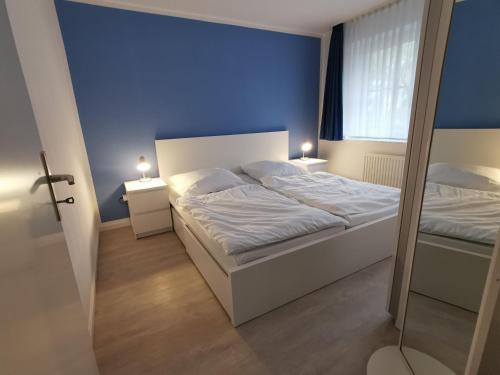ein Schlafzimmer mit 2 Betten und einer blauen Wand in der Unterkunft Kapitänshaus 11 in Laboe