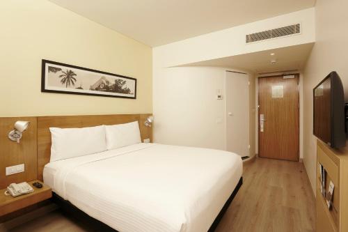 a bedroom with a white bed and a television at ibis Pune Viman Nagar - An Accor Brand in Pune