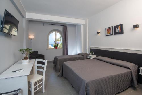 a hotel room with two beds and a desk at Hotel Hopps in Mazara del Vallo