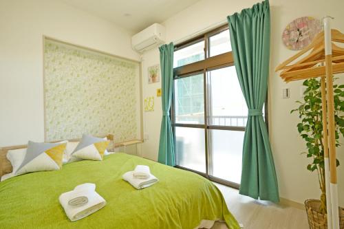 a bedroom with a green bed and a window at Oji Natural Cosy House in Tokyo